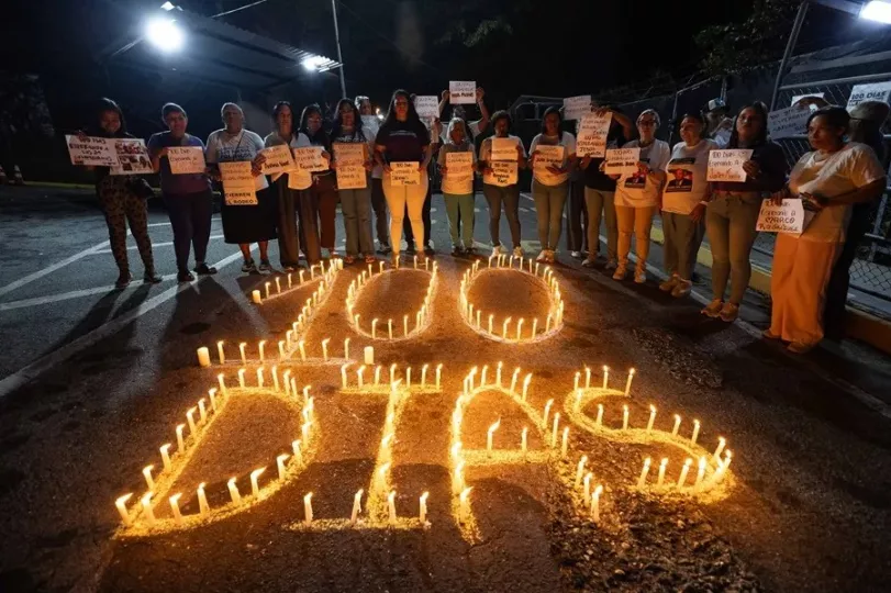 Familiares de presos políticos venezolanos sostienen pancartas durante una vigilia de 100 días frente a una cárcel.