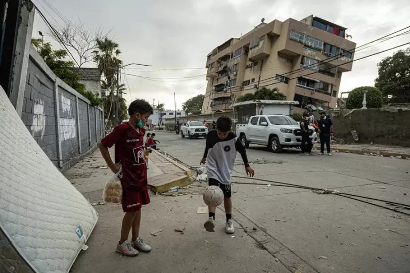 Niños juegan fútbol frente a un edificio afectado por un terremoto, el 27 de junio de 2026, en La Guaira (Venezuela). 