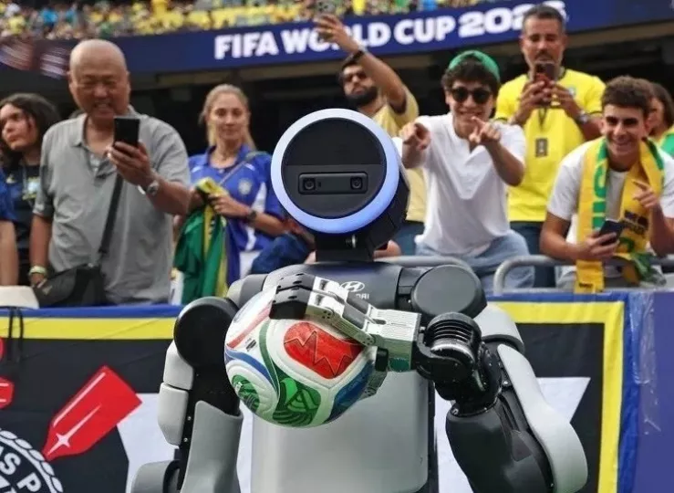 El robot humanoide Atlas realizando una pose de celebración de gol en un estadio de fútbol.