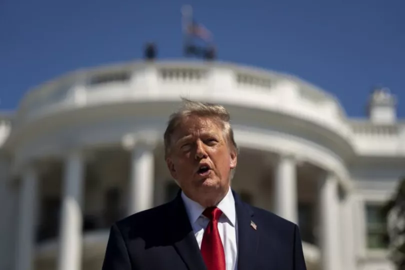 El presidente, de EE.UU, Donald Trump, habla con la Casa Blanca de fondo.
