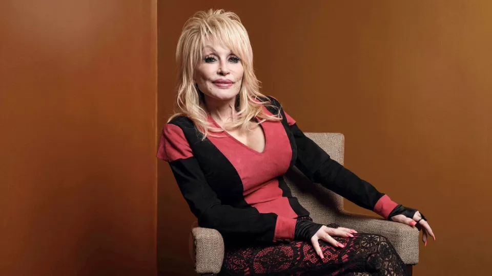 Fotografía de archivo de Dolly Parton sonriendo con su característico estilo.