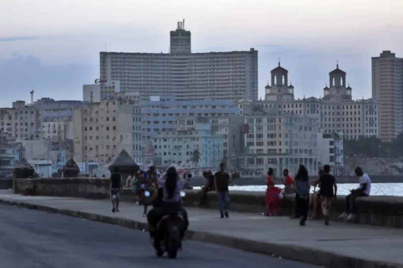 Personas caminando por el malecón durante una jornada de apagón.