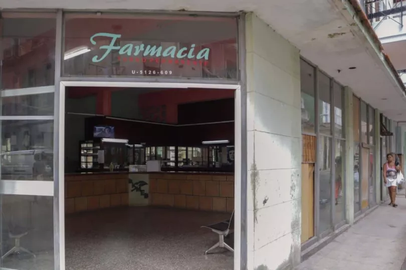 Vista exterior de una farmacia en Cuba con letreros informativos sobre la disponibilidad de medicamentos.