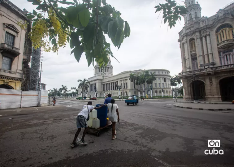 Familia cubana recolectando agua desde un punto de suministro lejano.