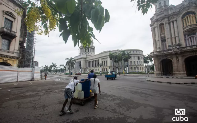 Familia cubana recolectando agua desde un punto de suministro lejano.